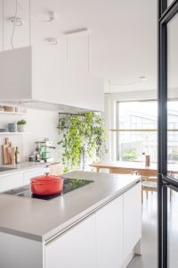 Moderne witte keuken op een gietvloer. Met warme houten eetkamerset. Interieuradvies Houthavens Amsterdam.